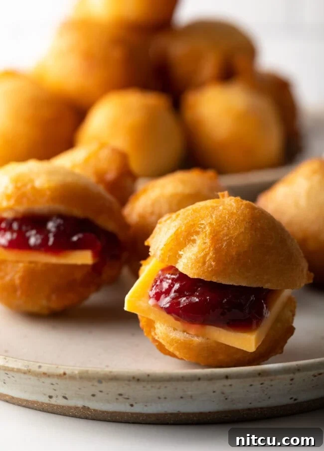 A close-up view of a Vetkoek cut open, revealing luscious cheese and sweet jam filling.