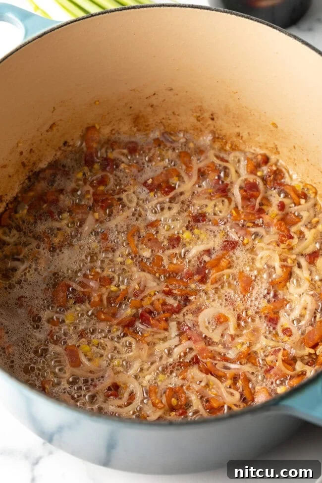 Bacon and shallots cooking in a pot.
