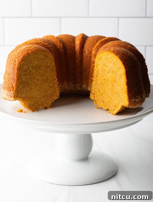 A slice of sweet potato pound cake on a plate, revealing its dense, moist interior and appealing orange hue.