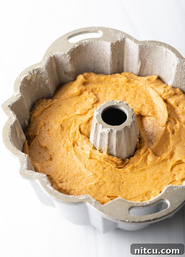 Cake batter smoothly filled into a greased Bundt pan, ready for baking.