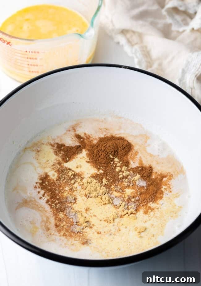 Large mixing bowl filled with half and half, beaten eggs, sugar, vanilla, and various spices, all waiting to be whisked together.