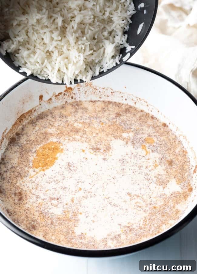 Adding fluffy cooked white rice to the creamy custard mixture in a large bowl, preparing for the final bake.