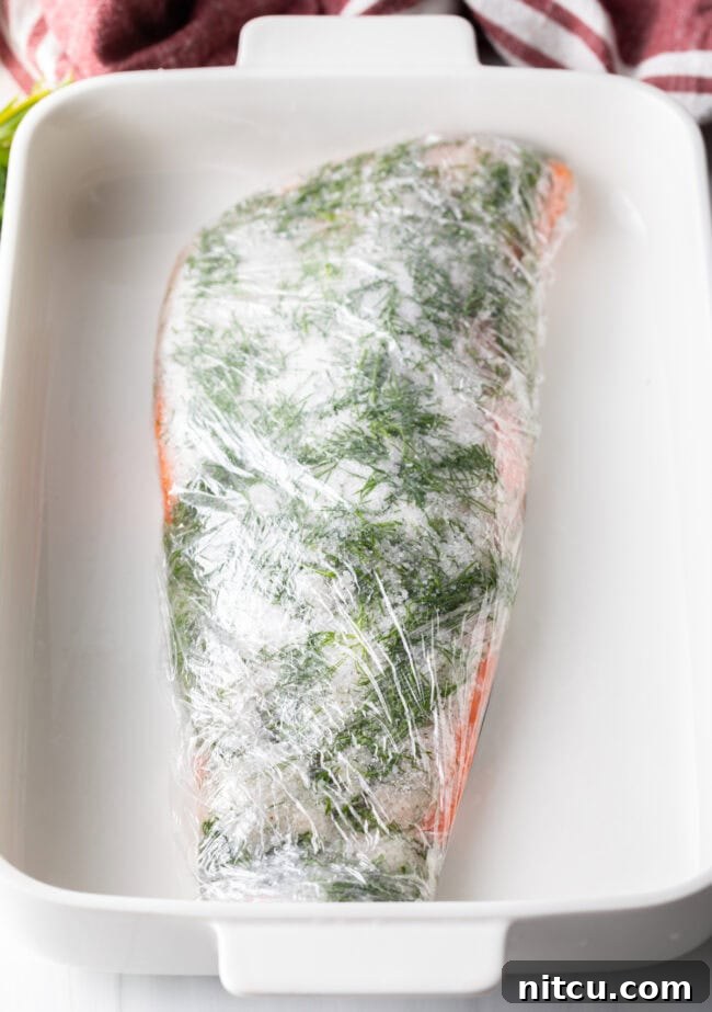 Salmon fillet wrapped tightly in plastic wrap, ready for pressing.