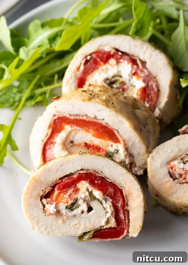 Sliced chicken roulade pieces on a plate with close view of cut section, showcasing the vibrant filling.