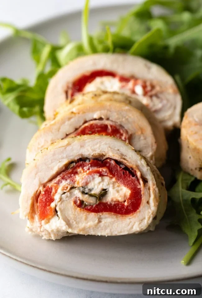 Close view pieces of chicken roulade on a plate, showcasing texture and rich filling.