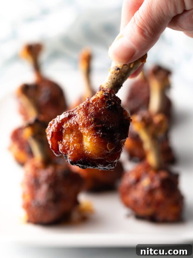Hand holding chicken lollipop to camera.