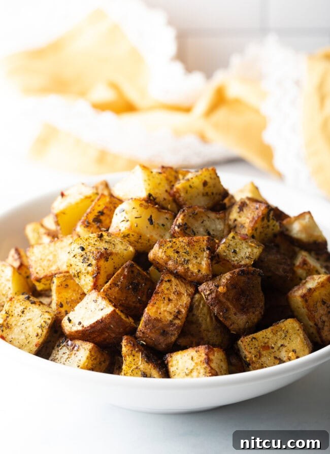 Cubes of roasted seasoned russet potato in a white bowl.
