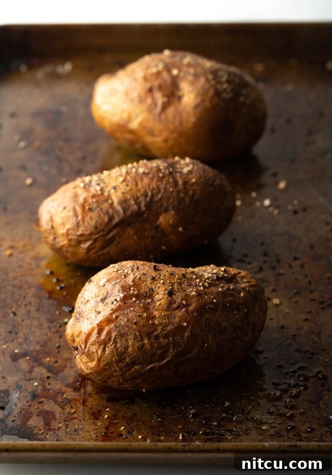 Russet Potatoes Recipe and Tips - Three baked potatoes on a baking sheet.