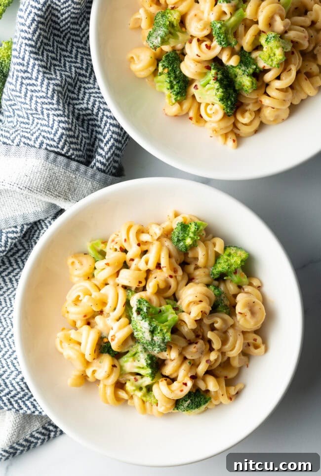 Top down view two bowls of broccoli pasta.