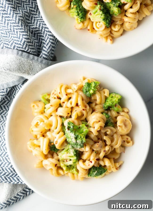 Two bowls top down pasta with boiled broccoli and cheese sauce.