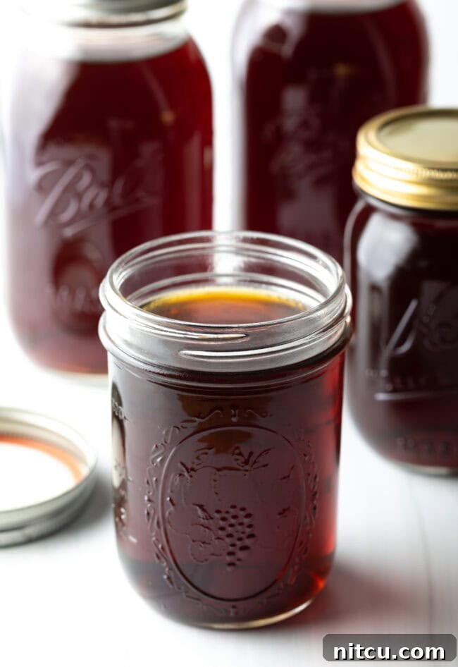 A glass jar filled with beef consomme with more jars in the background.