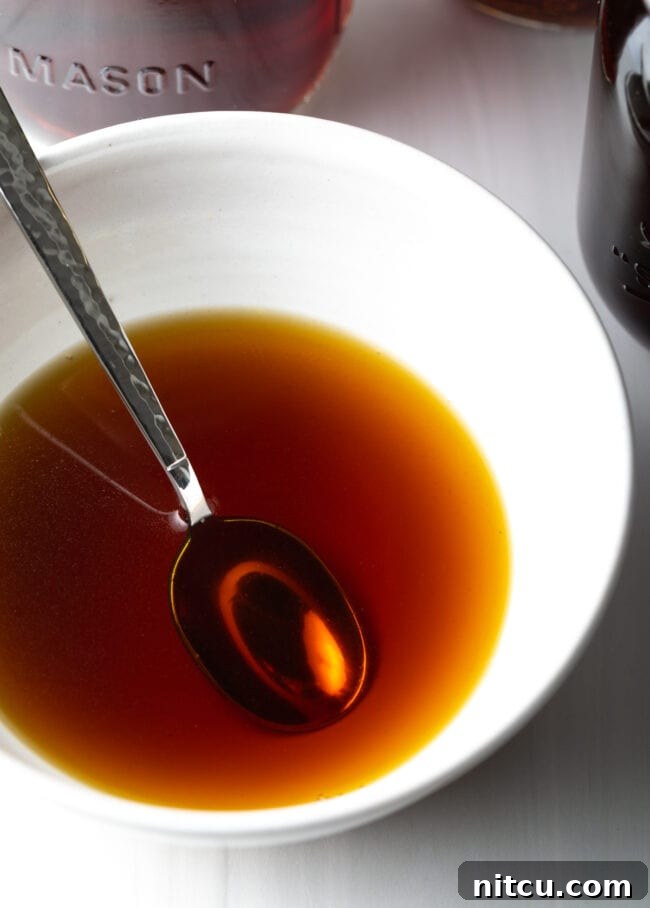 Metal spoon in a white bowl with homemade beef consommé.