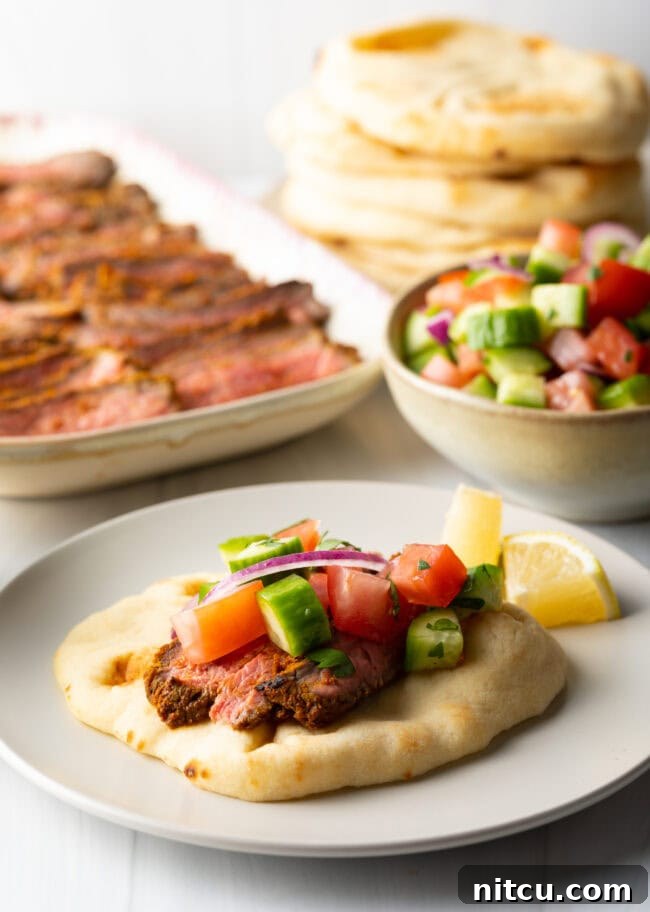 Beef shawarma recipe on naan, topped with chopped cucumbers and tomatoes.