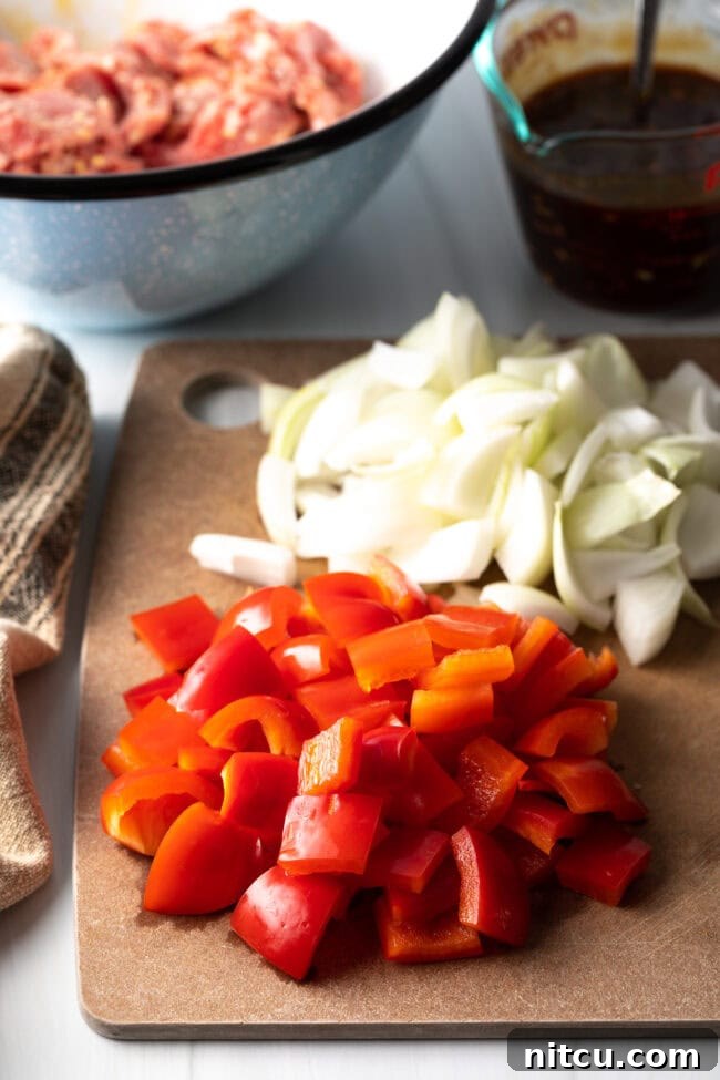 Chopped onion and red peppers on a cutting board.