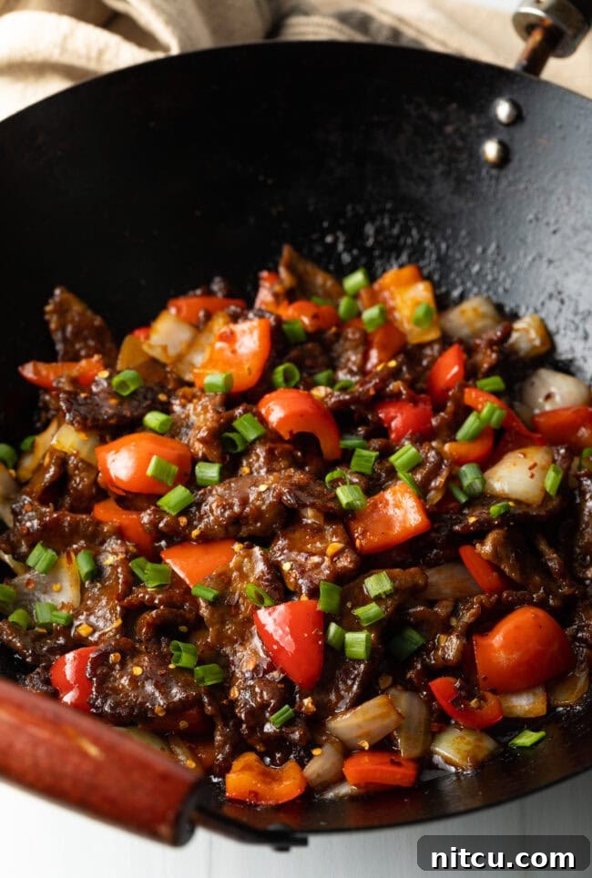 Top down view stir fry beef with veggies in a wok.
