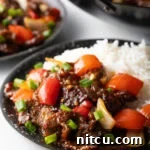Side view Beijing beef in a bowl with rice.