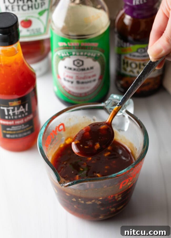 Hand showing spoon with sauce towards camera.