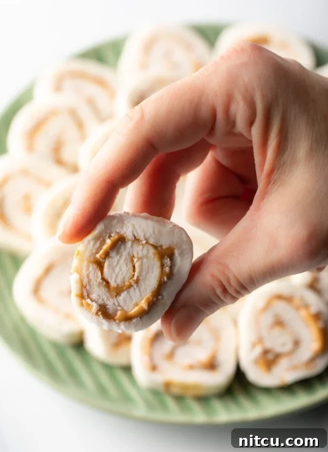 Hand holding slice of potato and peanut butter candy recipe to camera.