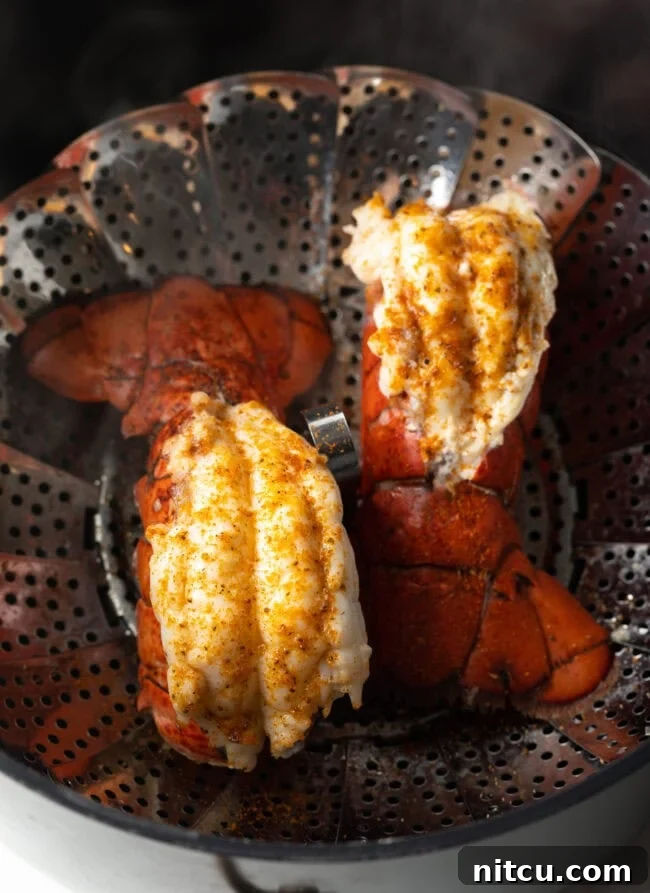 Two beautifully cooked lobster tails, vibrant red and tender, resting in a steaming basket, ready to be enjoyed.