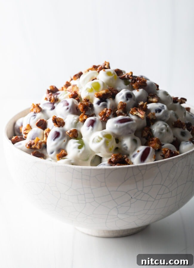 Side view of creamy salad with grapes in a white bowl.