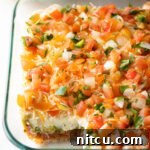 View of glass dish with portion missing, showing all 5 layers of the Mexican bean dip.