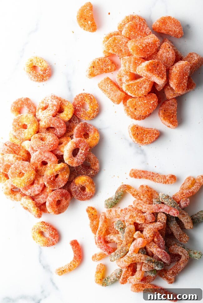 Top down view of four piles of dulces enchilados gummy candies, each now vibrantly coated with chamoy and tajin seasoning.