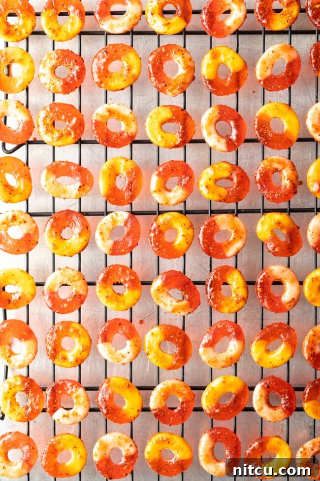 Chamoy and Tajin coated gummy candy rings laid out in neat rows on metal drying racks.
