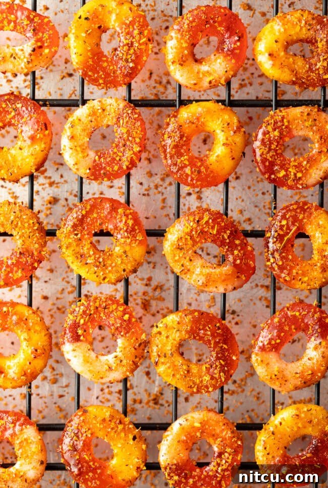 Close-up of Chamoy and Tajin coated gummy candy rings drying on metal racks.