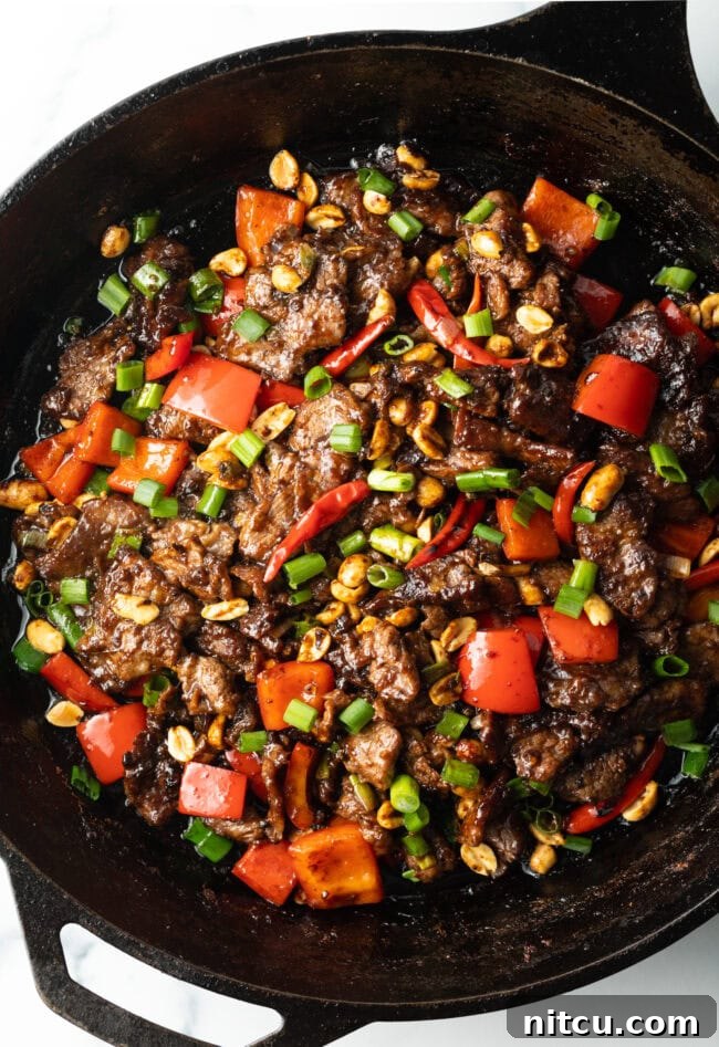 Chopped beef, red bell peppers, and scallions cooked together in a cast iron skillet, ready to be served.
