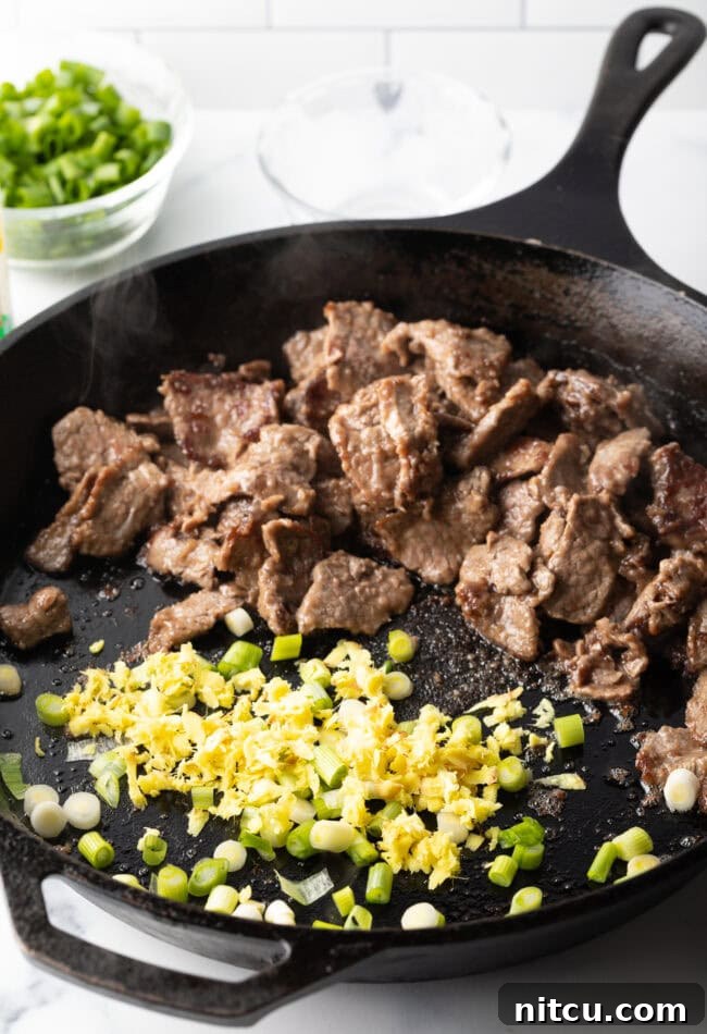 Cooked steak, garlic, and onions stir-frying in a skillet, close up.