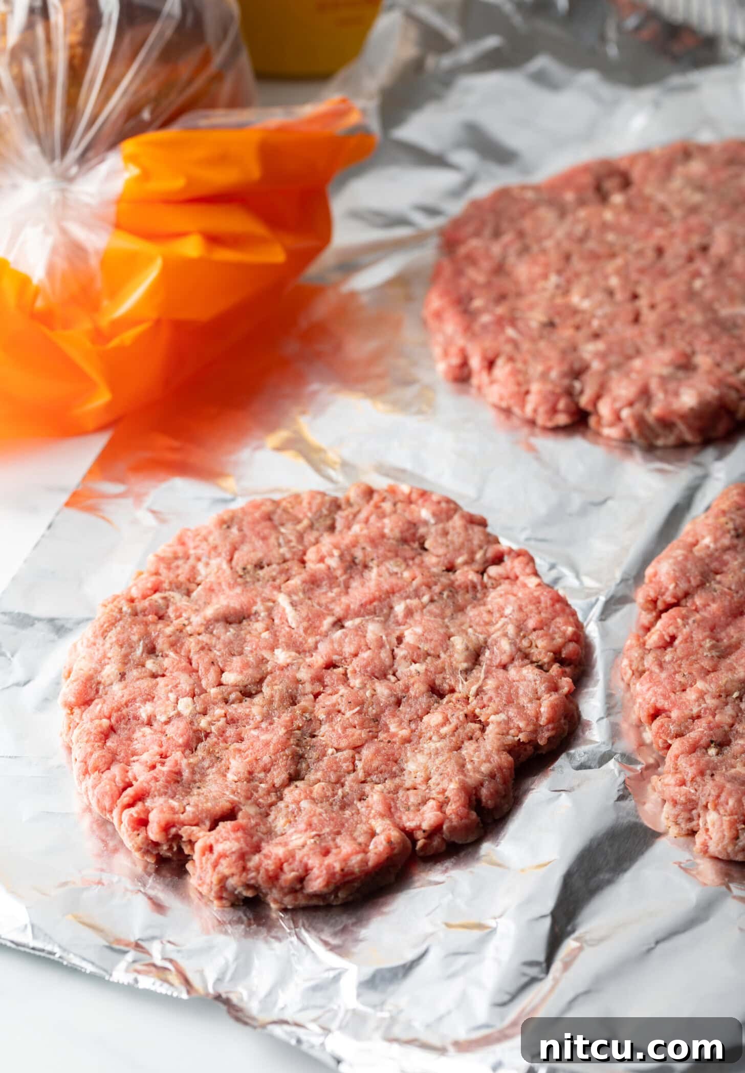 Raw burger patty on parchment.