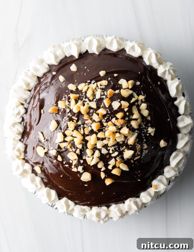 A top-down view of Duke's Hula pie, beautifully piped with whipped cream and generously topped with chopped macadamia nuts.