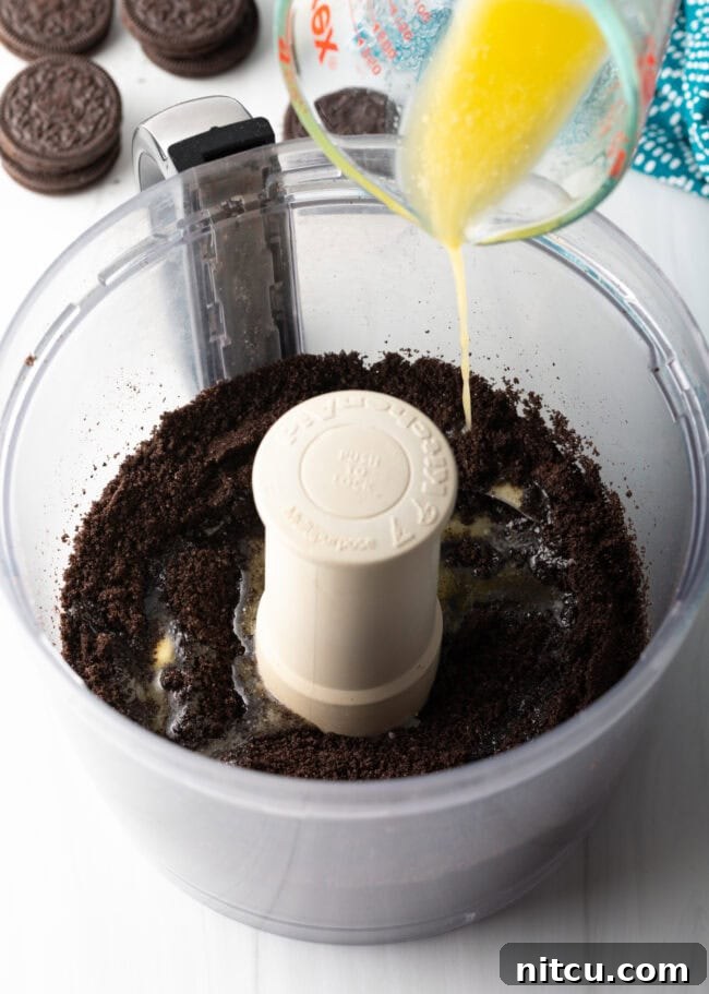 Melted butter being added to crushed Oreos.