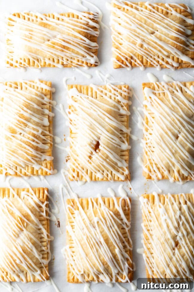 Top-down view of eight finished peach hand pies, each drizzled with luscious white icing, looking perfectly tempting and ready to serve.