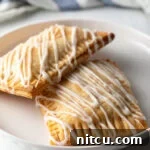 Two homemade peach pop tarts resting against each other on a white plate, ready to be enjoyed.
