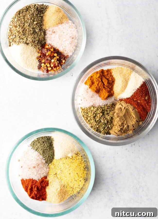 Top down view three bowls, each with a different blend of chicken seasoning.