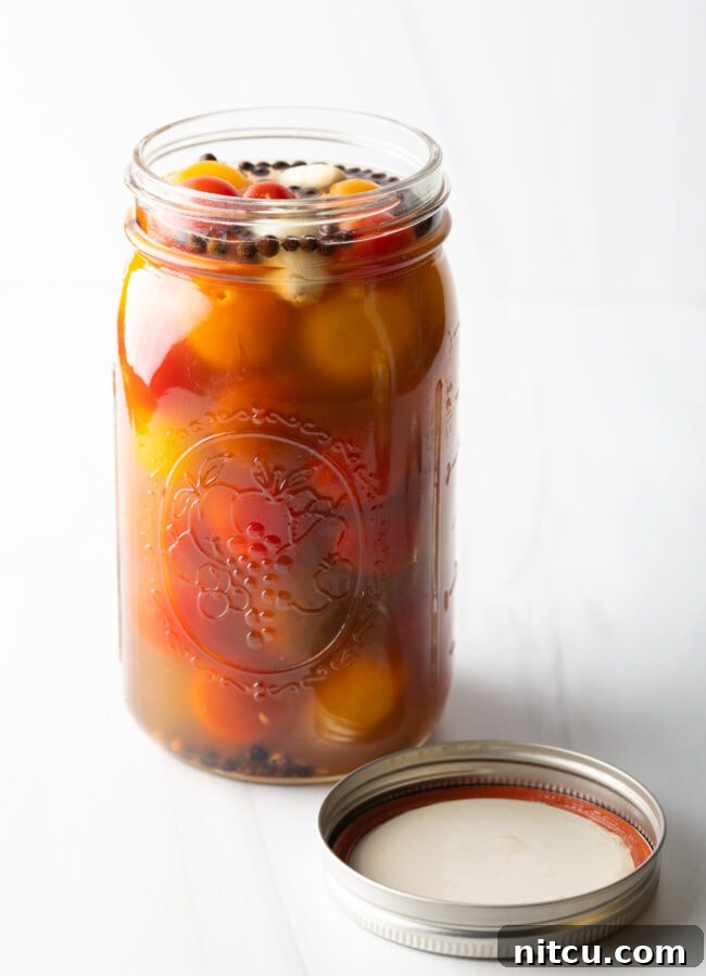 Marinated pickled cherry tomatoes in a large glass jar.