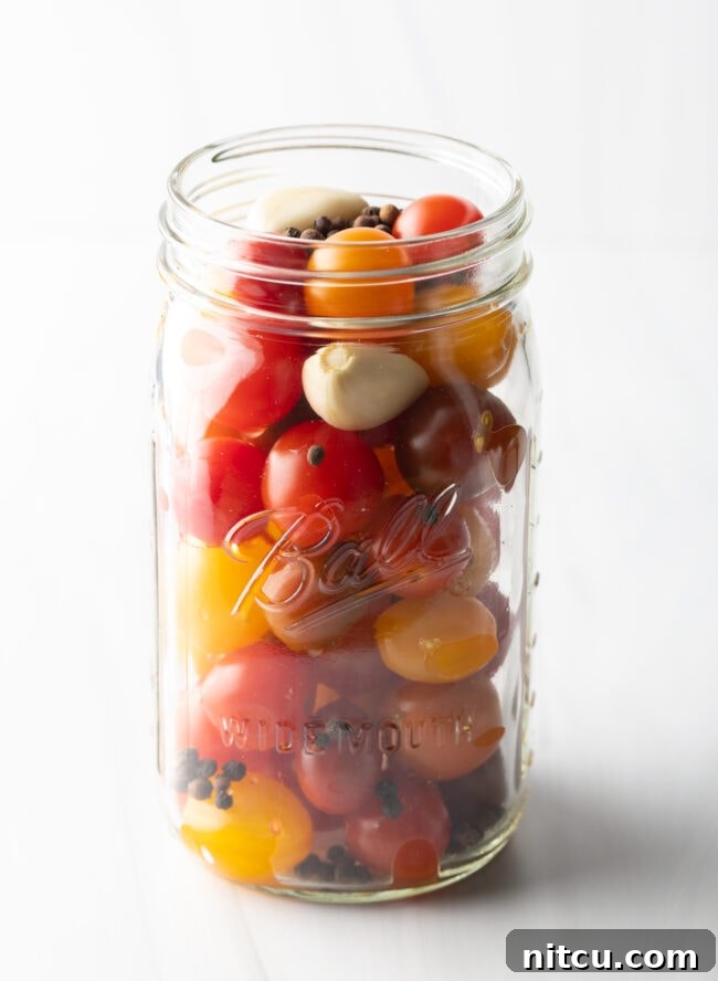 Small yellow and red cherry tomatoes in a large glass ball jar.