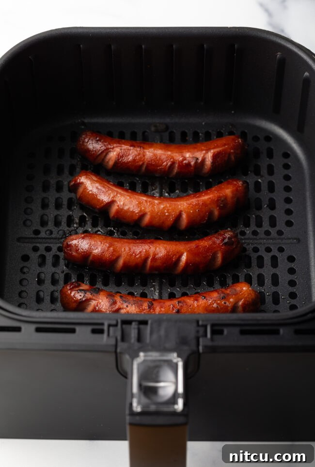 Cooked dark brown hot dogs in the fryer basket.