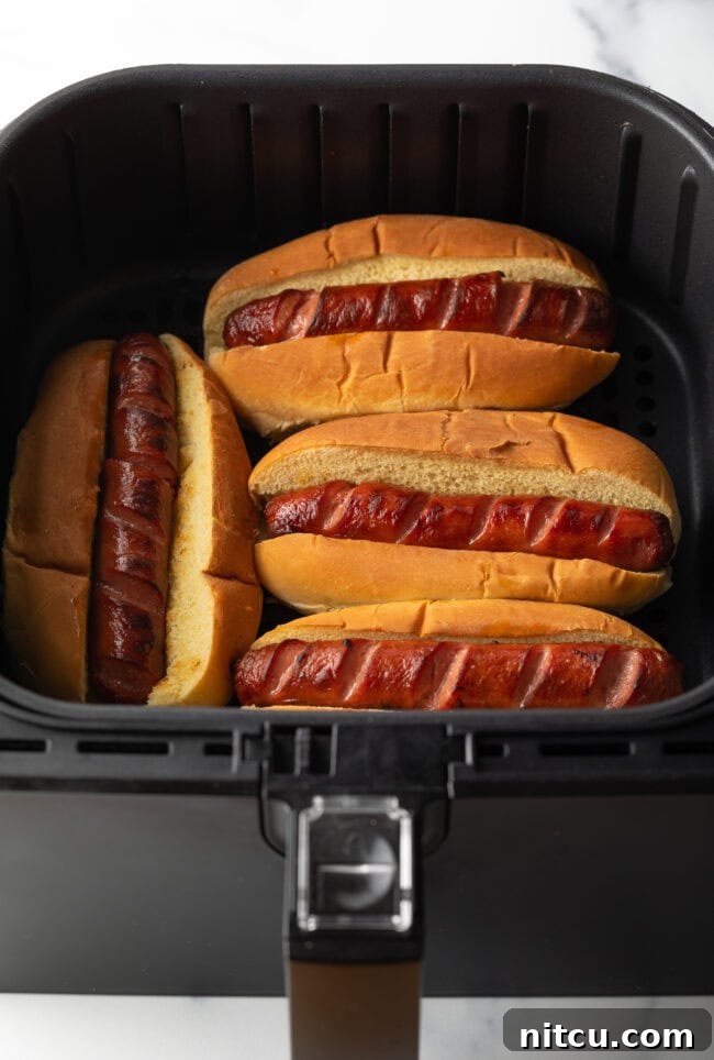 Toasting four hot dogs in buns in an air fryer.