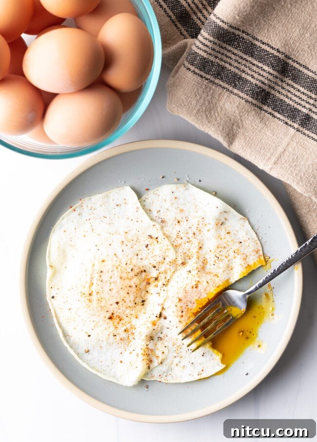 Fork cutting into the soft yolk of a gently over easy fried egg, on a light blue plate.