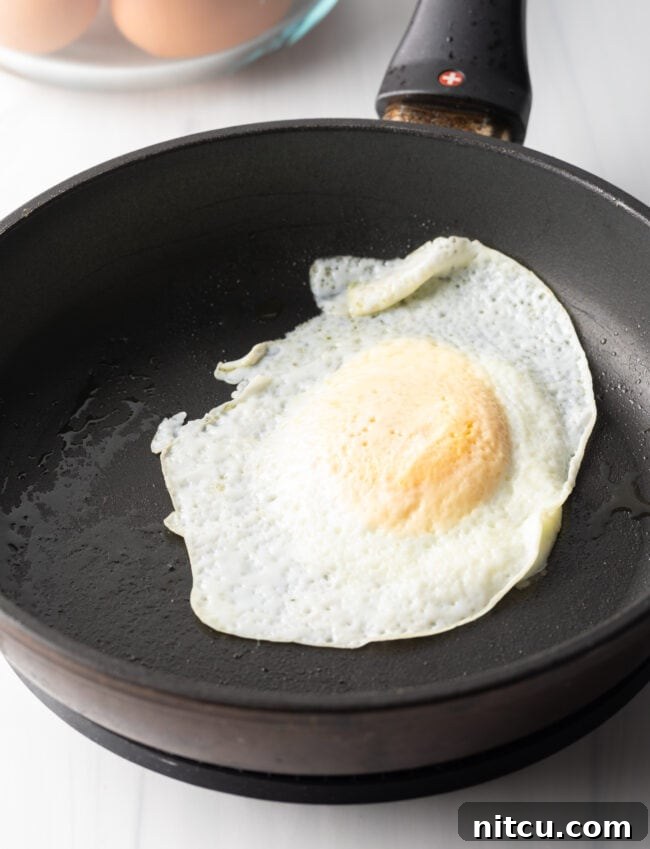 Soft fried egg over easy in a black nonstick skillet.