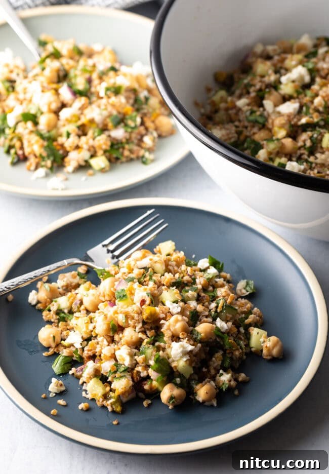 Blue plate with a generous serving of Jennifer Aniston bulgur wheat salad, with a metal fork on the plate.