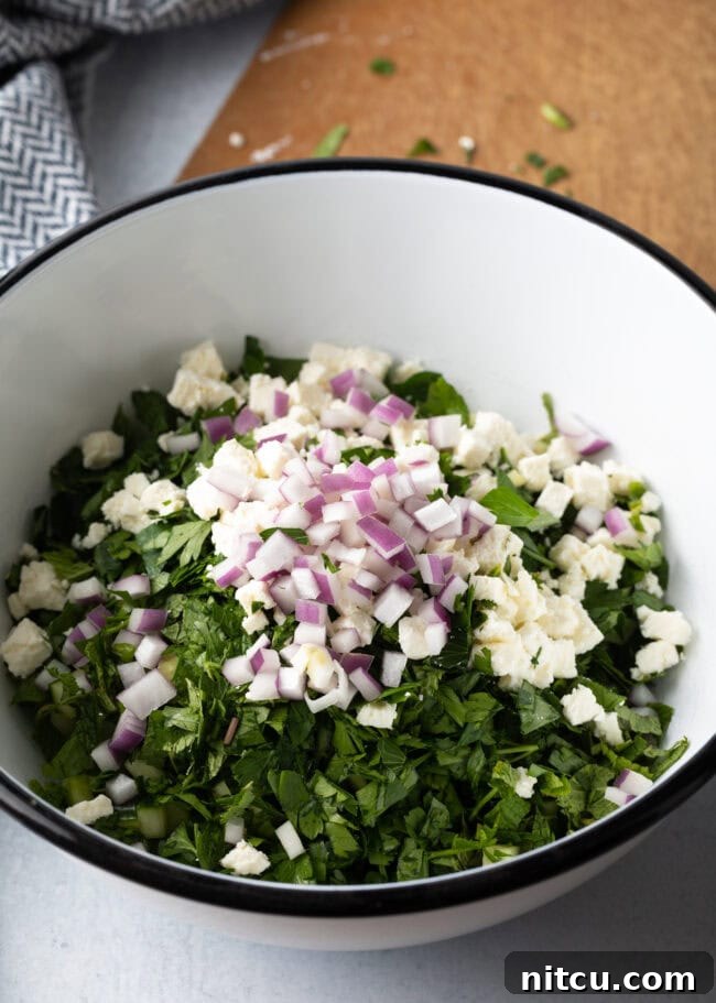 Chopped veggies and bulgur in a large white bowl.