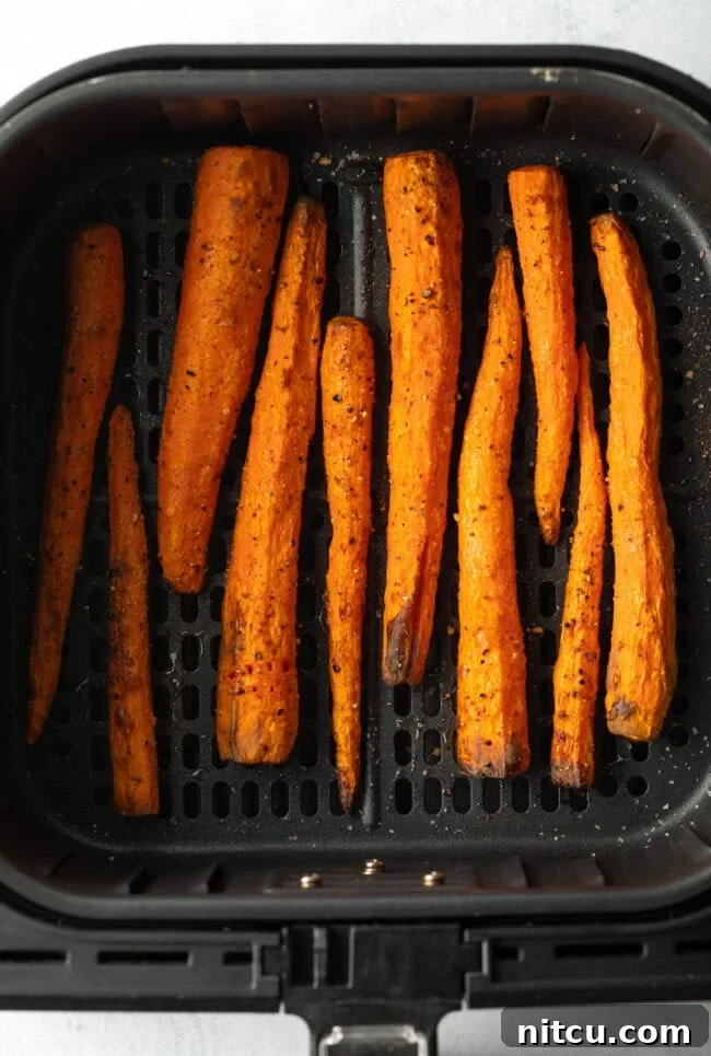 Top down view vertical pile of whole roasted carrots in the fryer basket.