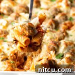 Metal spoon holding a serving of meatball casserole to camera.