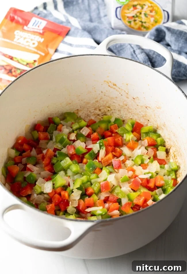 Diced bell pepper and onion in a white cooking pot.