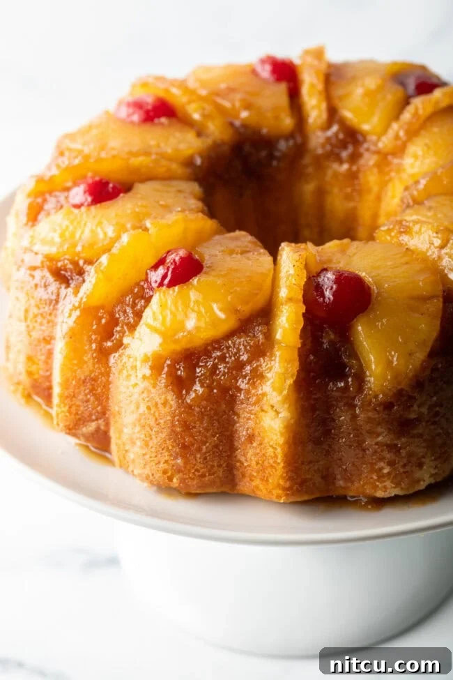 Close-up view of a beautifully baked pineapple upside down Bundt cake, artfully topped with glistening maraschino cherries.
