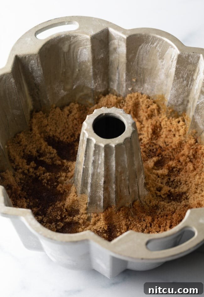 A Bundt pan with a layer of brown sugar lining its bottom, ready for the fruit.