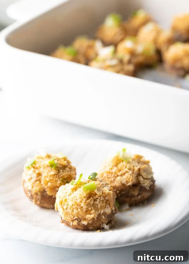 3 baked seafood crab stuffed mushrooms on a white plate.